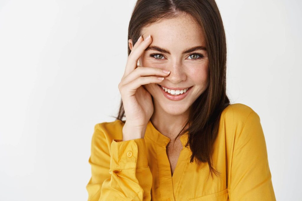 Chica feliz y sonriente mira a la cámara, su rostro es muy armonioso después del microinjerto de cejas