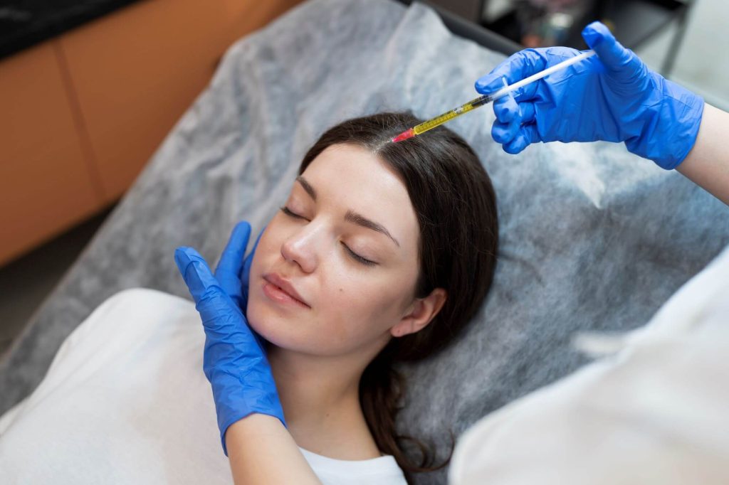 Doctor aplica inyección de plasma rico en plaquetas en el cuero cabelludo de mujer joven